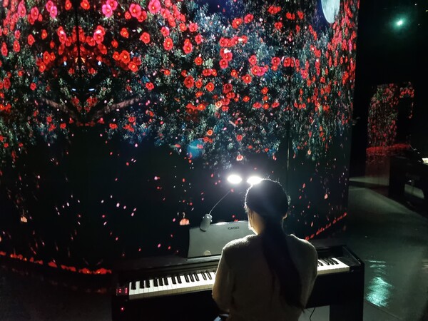 아르떼뮤지엄 여수 꽃 부스에서 피아노 치는 모습(사진=최재혁기자)